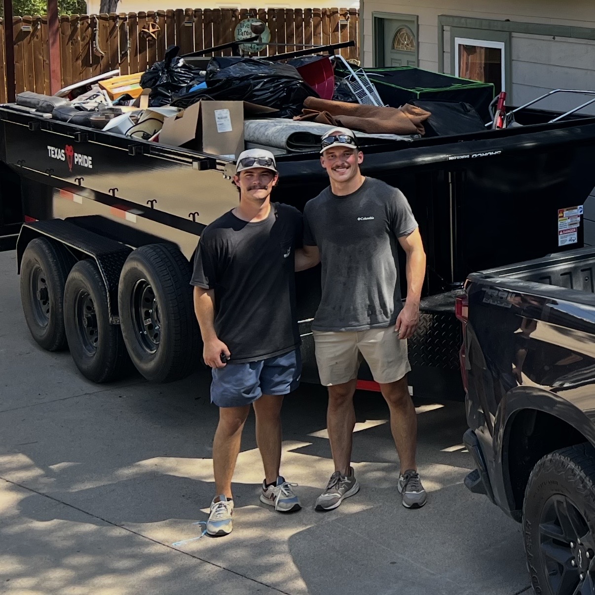 Bye Pile Junk Removal crew members standing in front of a loaded dump trailer in Granbury, TX